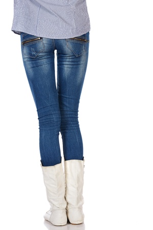 Legs and boots of a stylish and thin black african young adult woman casually dressed in blue jeans and white boots and isolated on a white backgroundの写真素材