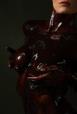 Beautiful and sexy caucasian nude young adult woman covered in sweet running chocolateの写真素材