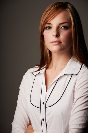 Beautiful young caucasian adult woman with long auburn red hair on a plain background, wearing a white button shirt の写真素材