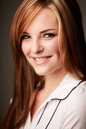Beautiful young caucasian adult woman with long auburn red hair on a plain background, wearing a white button shirt の写真素材