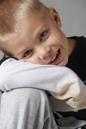 5 year old caucasian boy with short blonde hair, blue eyes and a light, healthy complexion wearing a long sleeve t-shirt. Shot in studio on a grey background.の写真素材