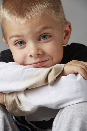5 year old caucasian boy with short blonde hair, blue eyes and a light, healthy complexion wearing a long sleeve t-shirt. Shot in studio on a grey background.の写真素材