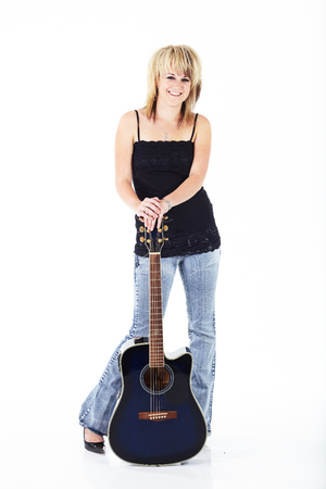 Beautiful young blonde caucasian woman standing with a blue acoustic guitar against a white backgroundの写真素材