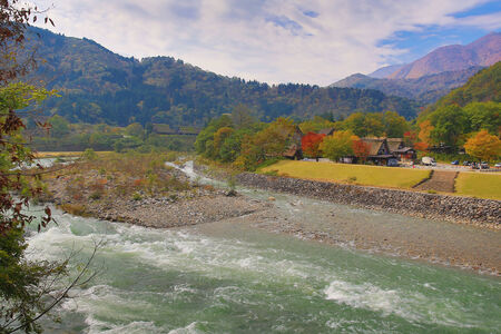 Beautiful Landscape In The Japanese Mountains With A Wild River, Red Bridge And Rock Covered By Typical Pinesの写真素材