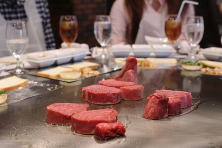 Japanese chef deliberately preparing and cooking traditional beef teppanyaki on a hot plateの写真素材