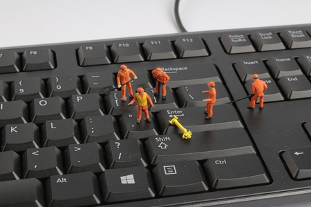 the Small figurines of workers repairing computer keyboardの写真素材