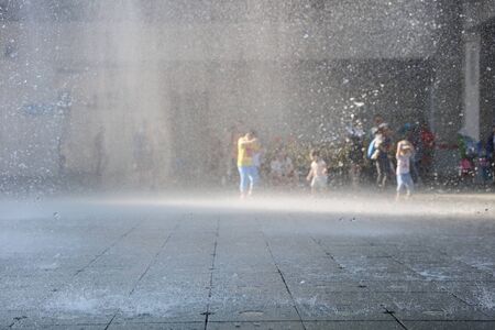 happy kid playing with fountain in front of buildingのeditorial素材