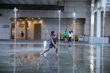 happy kid playing with fountain in front of buildingのeditorial素材