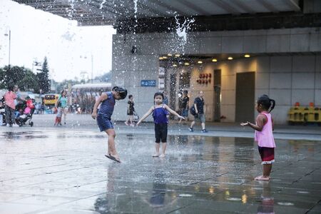 happy kid playing with fountain in front of buildingのeditorial素材