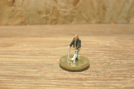 the small  man with crutch isolated on coinsの写真素材
