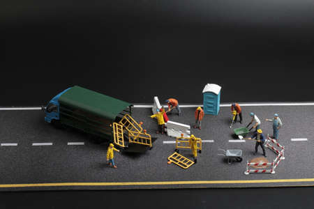 Mini figure with warning sign on concrete street crackedの写真素材