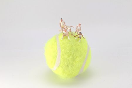 A Tiny toys play tennis on the big tennis ballの写真素材