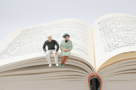 the fun of Mini people:figure sitting on bookの写真素材
