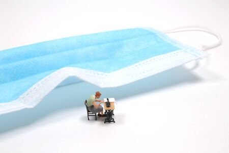 the mini figure of gloves sew reusable cloth protective face mask with sewing machineの写真素材