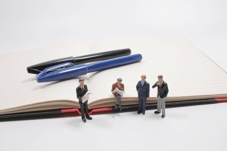 mini people standing with fountain pen on paper with white background.の写真素材