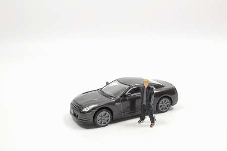 a figure man stands in front of his new car