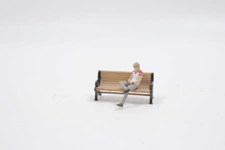 a figure sitting on bench and use her phone in parkの写真素材