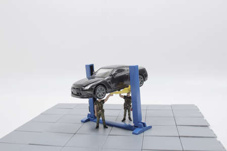 a Mini figure mechanic repairing dusty car wheel,の写真素材