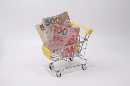 a Still life of shopping cart and hk notes on turquoise background