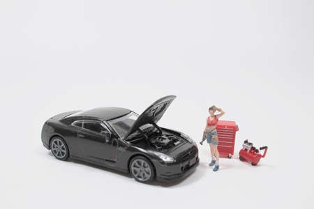 Mini figure mechanic repairing dusty car wheel,の写真素材