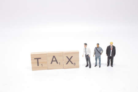 figure businessman standing beside colorful wooden TAX wordの写真素材