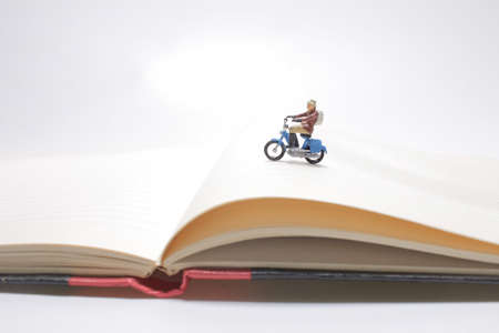 mini figure rides on a motorcycle over open diary book. Travel concept