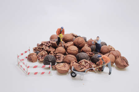 mini construction worker figurines working on opening walnuts