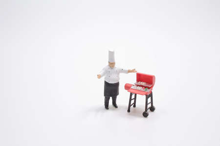 The mini Chef prepares meat on the barbecue.