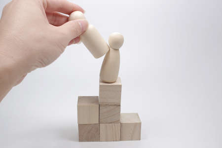 Hand puts wooden figure on podium shifting the figure standing there
