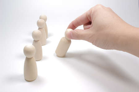 Wooden figures on a white background stand in a row and their male hand move