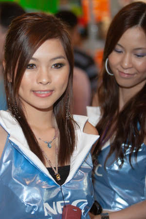 young hostesses stand next to products at the exhibition. 25 Aug 2007のeditorial素材