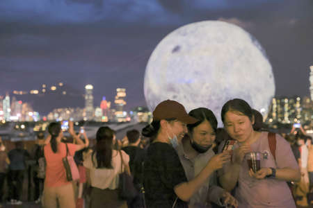 21 Sept 2021 People pose for pictures against the backdrop of a huge glowing moon floating in the Kwun Tong typhoon shelterのeditorial素材