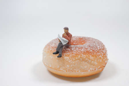 the figure man sit onm the big donut top read newspaper