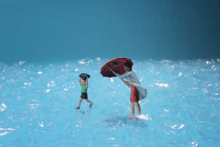 a mini figure walk ubder the rain with umbrella,の写真素材
