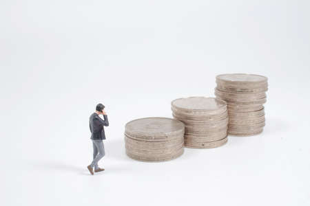 Growth concept. Businessman miniature figure walking to stack of coinsの写真素材