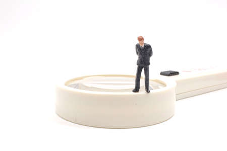 Magnifier and miniature people on the white boardの写真素材