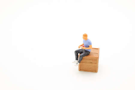 figure man wearing t-shirt and grey jeans sitting on a wooden crateの写真素材