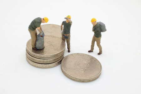 the Figurines of manual workers with stacks of coinsの写真素材