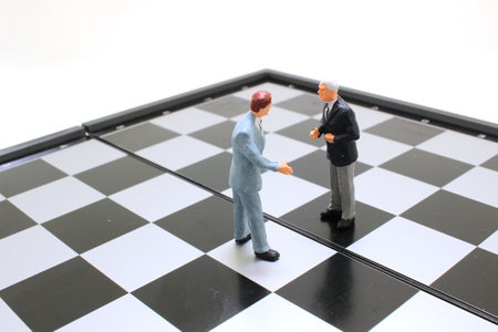 a Miniature people businessmen standing on a chessboard with a chess pieceの写真素材