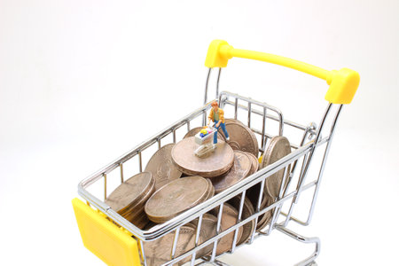 mini shoppers with shopping cart on stack of coins.の写真素材
