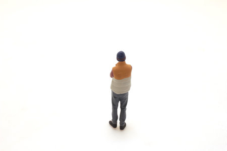 Isolated miniature figurine standing with hands behind back