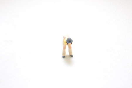 a Miniature Figure of Bending Person on White Backgroundの写真素材