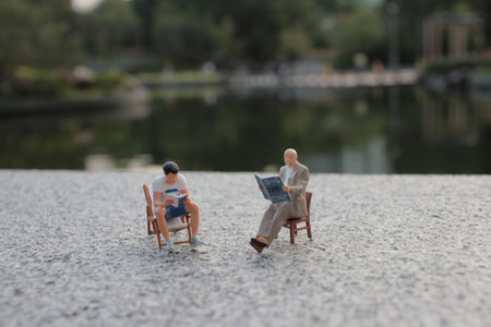 Miniature figures are seated outdoors near a serene lake,の写真素材