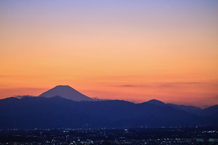 Dec 4 2024 dusk featuring glowing city lights and silhouetted mountainsの写真素材