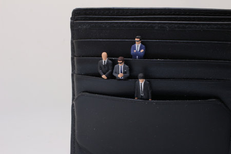 dressed in business suits placed within the compartments of a black wallet.