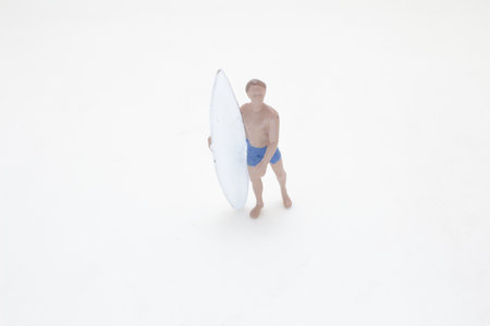 miniature figurine of a man holding a surfboard against a plainの写真素材