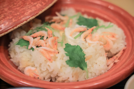 a garnished bowl of rice featuring small shrimp and fresh