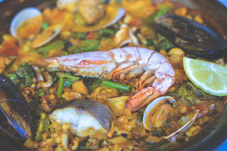 paella with shrimp, clams, and squid atop rice and vegetablesの写真素材