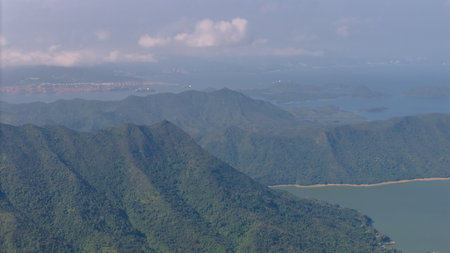 mountains in the foreground with a coastal city and vivid cloudy sky in the distance.の写真素材