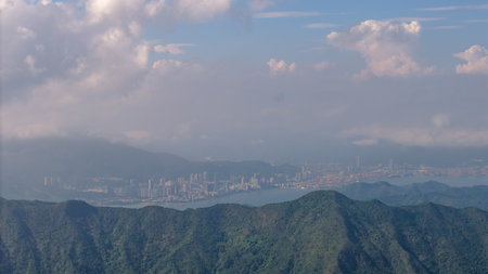 mountains in the foreground with a coastal city and vivid cloudy sky in the distance.の写真素材
